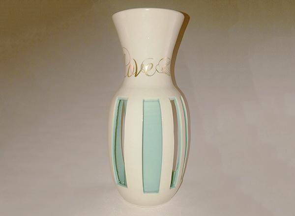Hand thrown, double walled, ceramic vase with white exterior, turquoise interior, and gold lettering.
