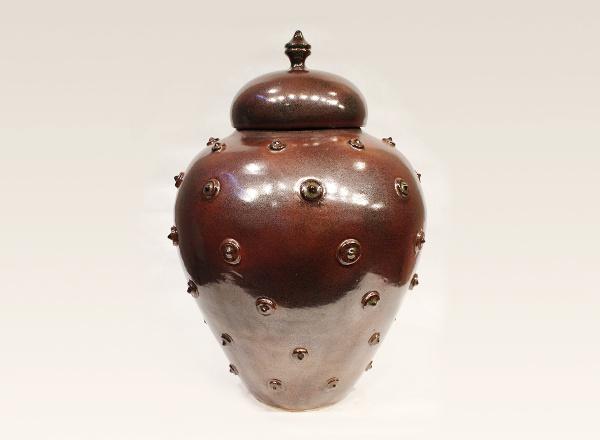 Large hand thrown covered jar with spiked surface and coffee colored glaze.