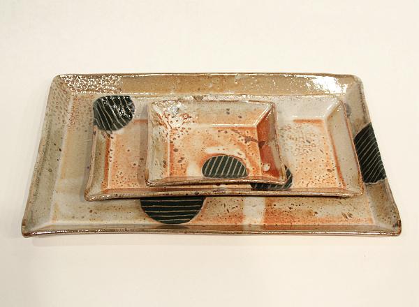 Stacking set of handmade serving trays with coffee colored glaze and embedded designs.