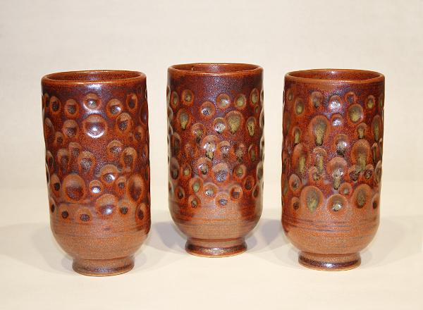 Three hand thrown drinking tumblers, each with coffee colored glaze.