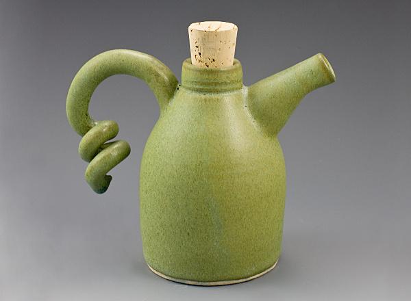 A hand thrown ceramic ewer with green glaze and corked lid.